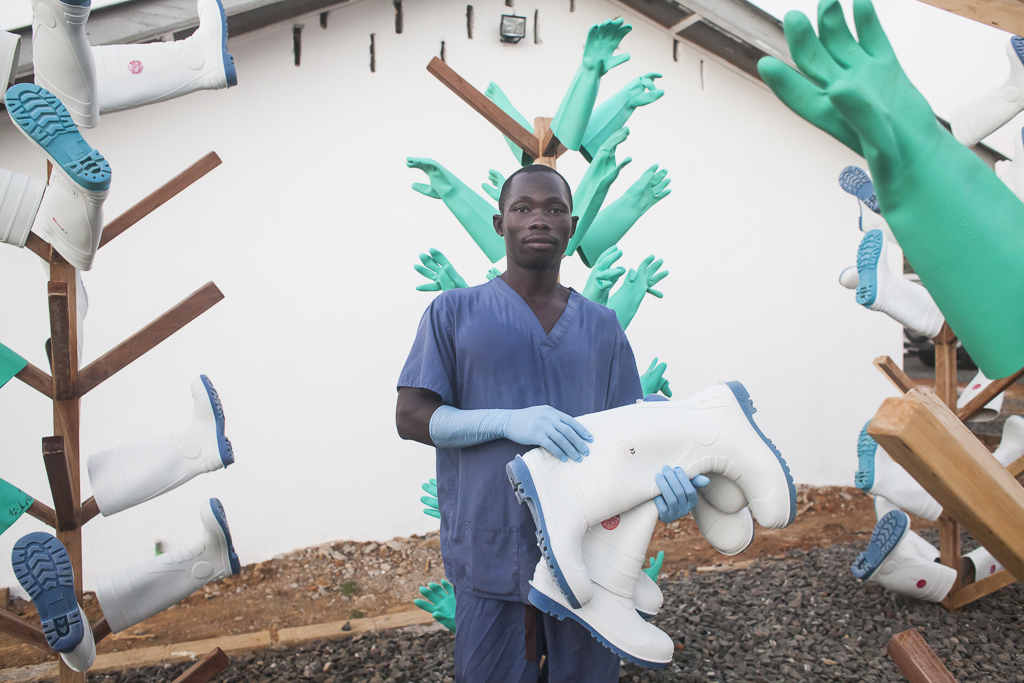 A Laundry officer in the drying area. The boots and gloves are part of the Personal Protective Equipment (PPE) for Ebola Virus Disease (EVD). After a soaking of 30 minutes in chlorine solution, boots and gloves are dried under the sun on these 